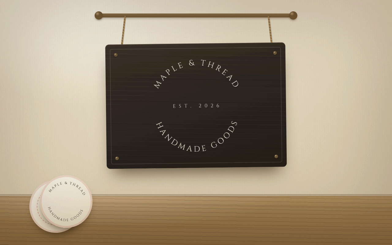 A hanging wooden shop sign carrying a circular mark that reads MAPLE AND THREAD, EST 2026, HANDMADE GOODS, with a stack of matching round stickers below it.